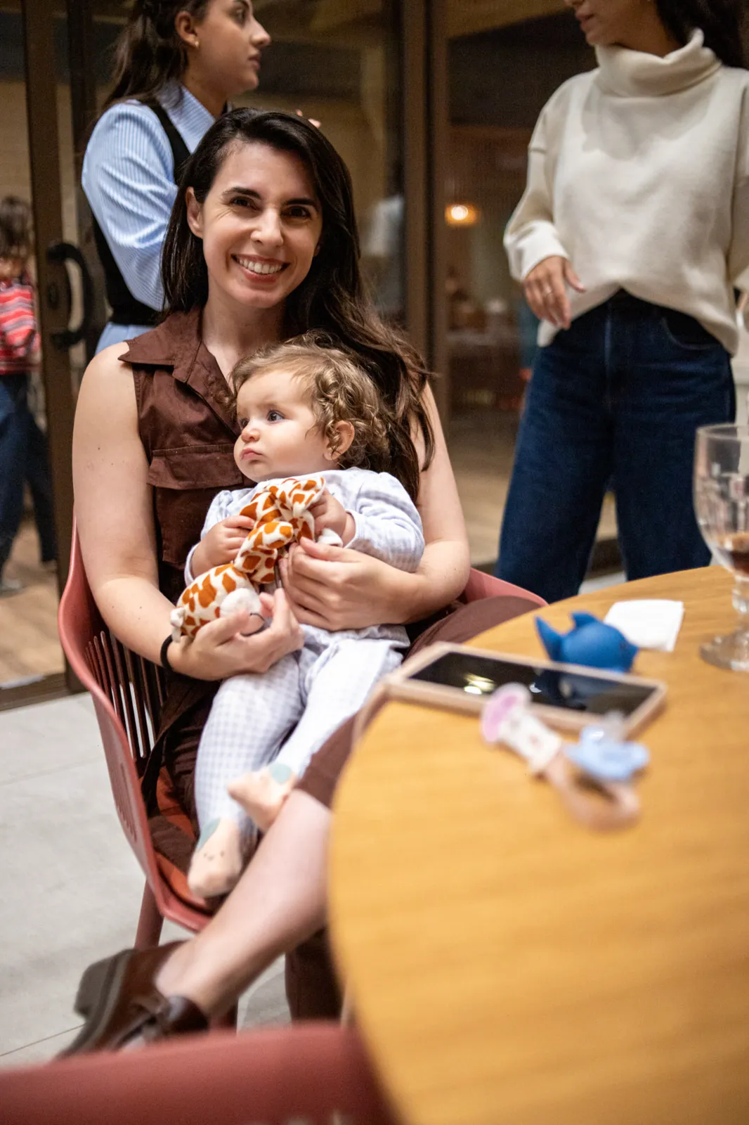Mãe sorrindo com o bebê no colo durante a festa
