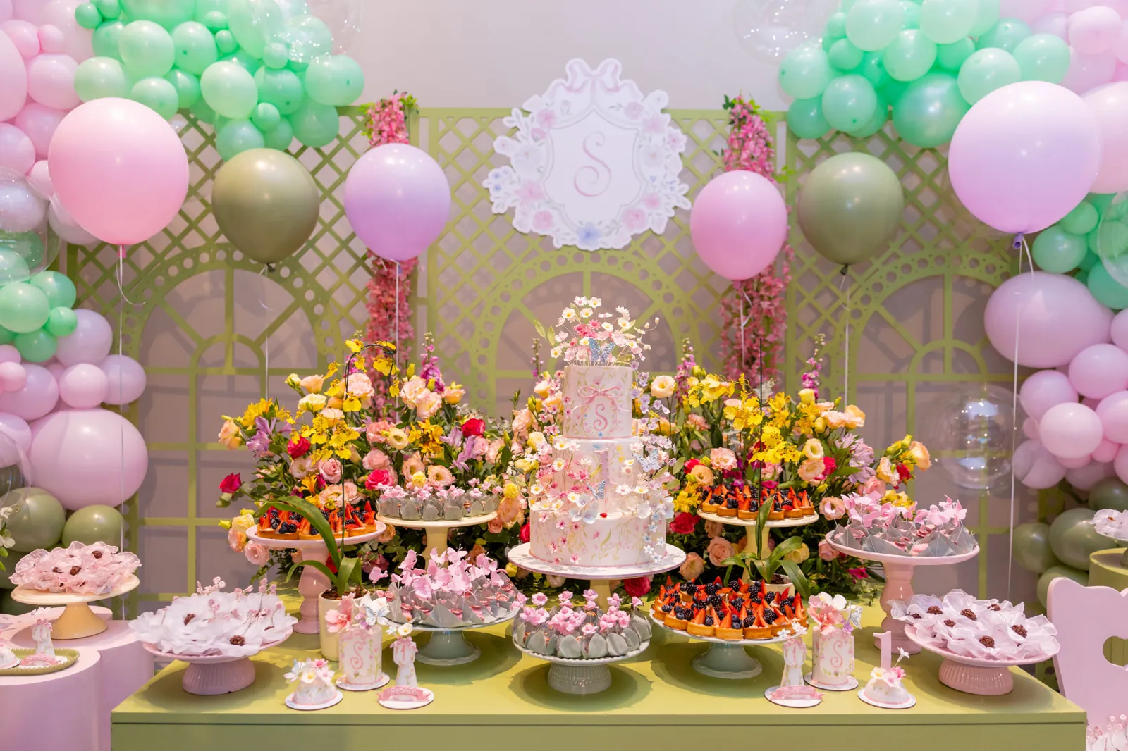 Mesa decorada de festa com bolo florido, balões e doces
